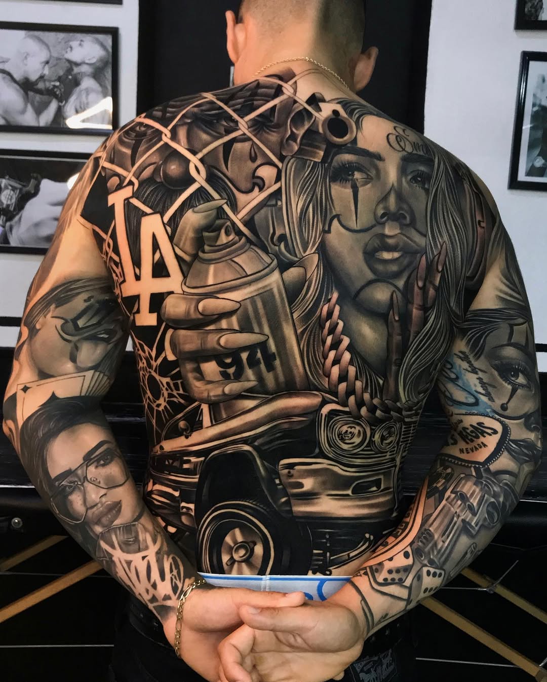 Large back tattoo featuring portrait of a woman with long hair, LA logo, and decorative elements in black and grey shading.