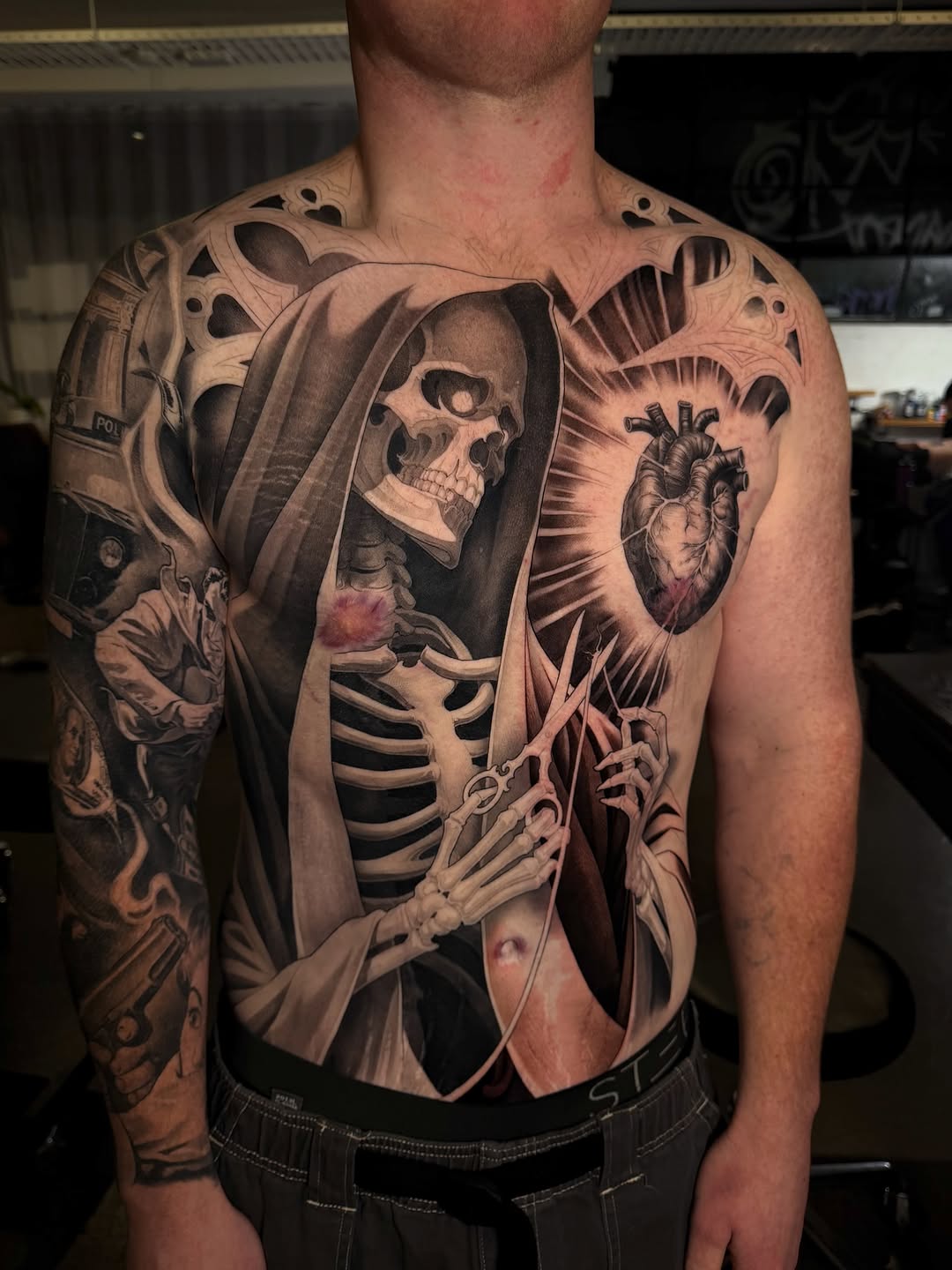 Grim reaper skeleton figure with hooded robe and anatomical ribcage, chest and torso placement, rendered in black and grey with soft shading.