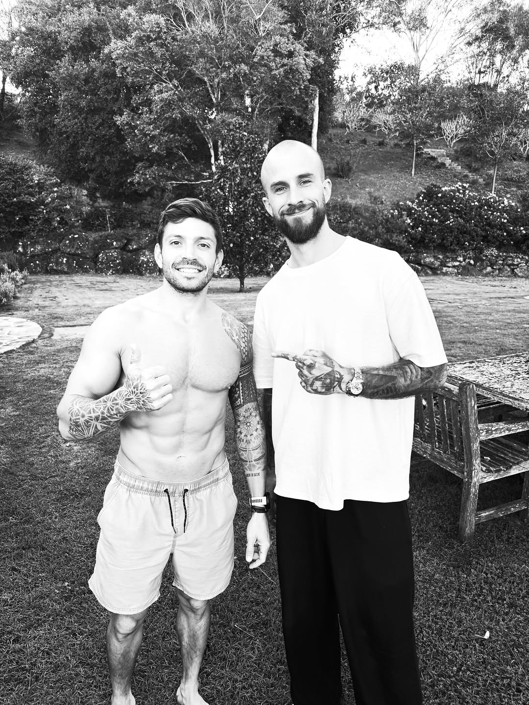 Man displaying extensive black and grey sleeve tattoos on both arms featuring intricate geometric and floral designs with smooth shading.