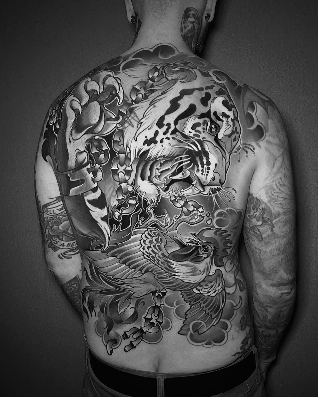 Large back piece featuring an ornate lion head with flowing mane and decorative clouds in black and grey shading.