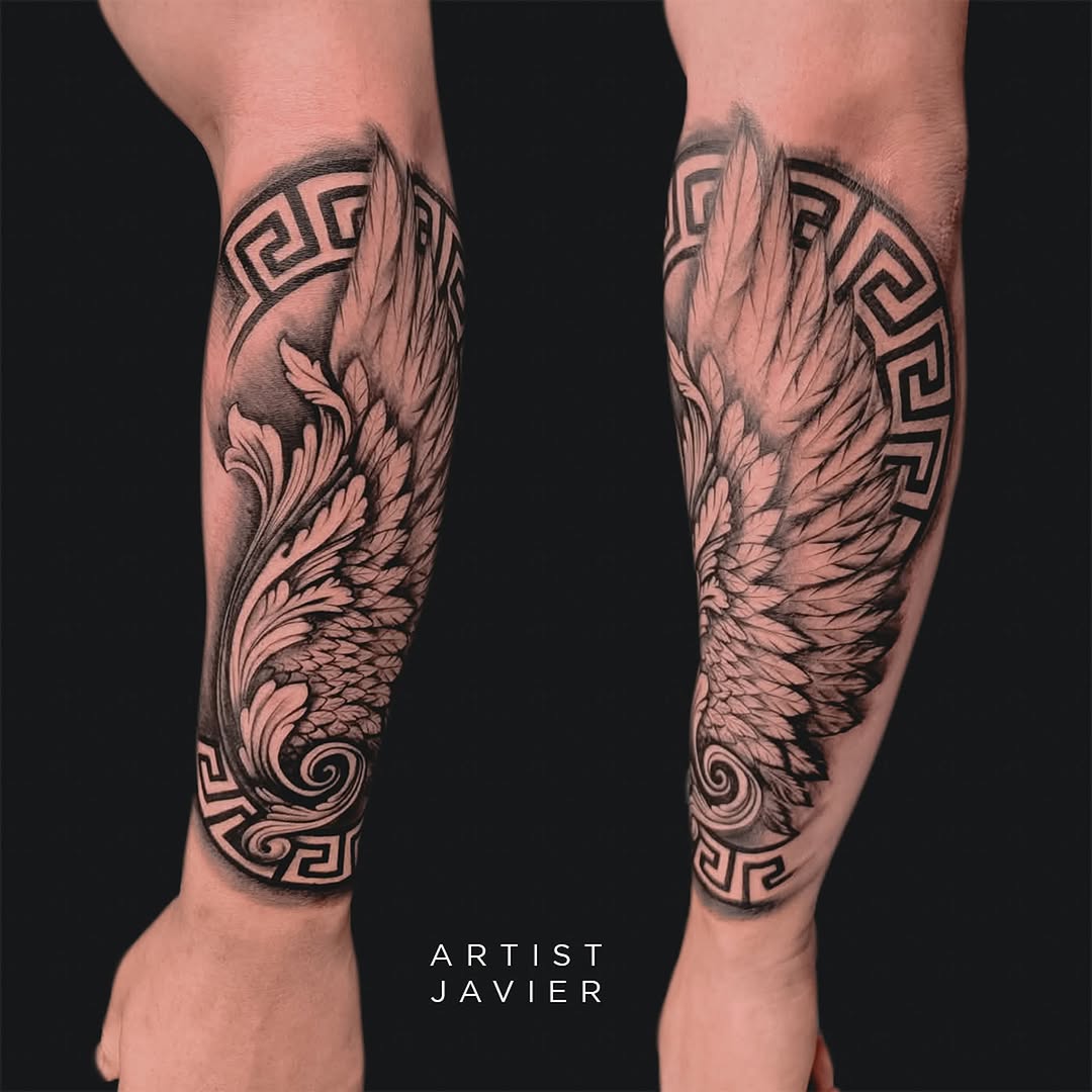 Matching winged tattoos on both calves featuring detailed feathered wings with ornamental Greek key patterns and spiral elements in black and grey.