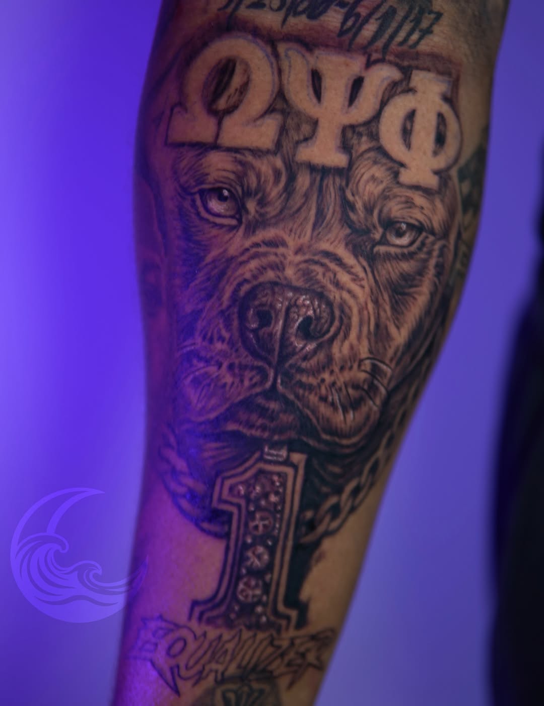 Black and grey bearded face tattoo with three eyes and mystical symbols on forearm, featuring detailed shading and decorative elements.