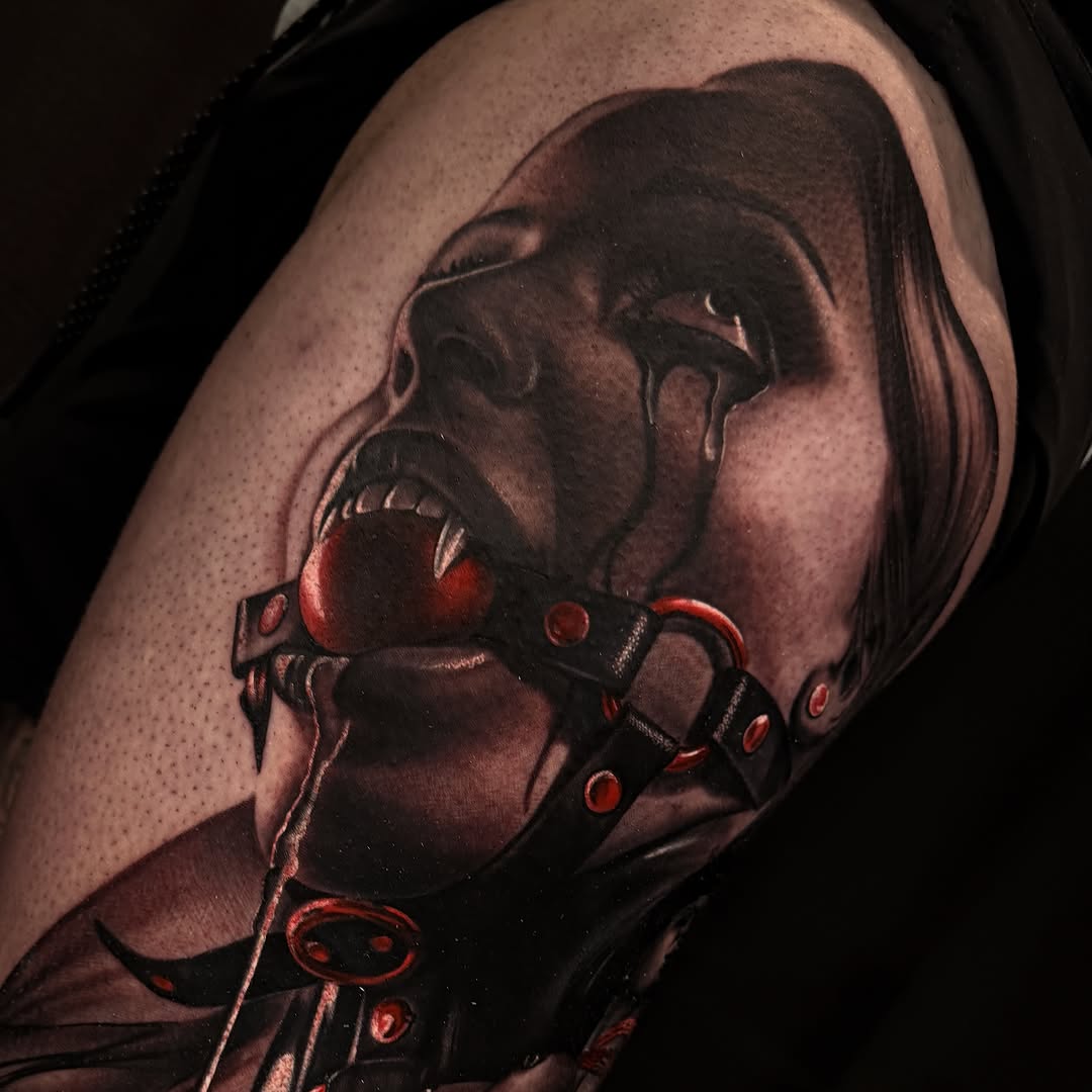 Vampire head with fangs and ornate red-jeweled leather collar on upper arm, rendered in black and grey with red accents.