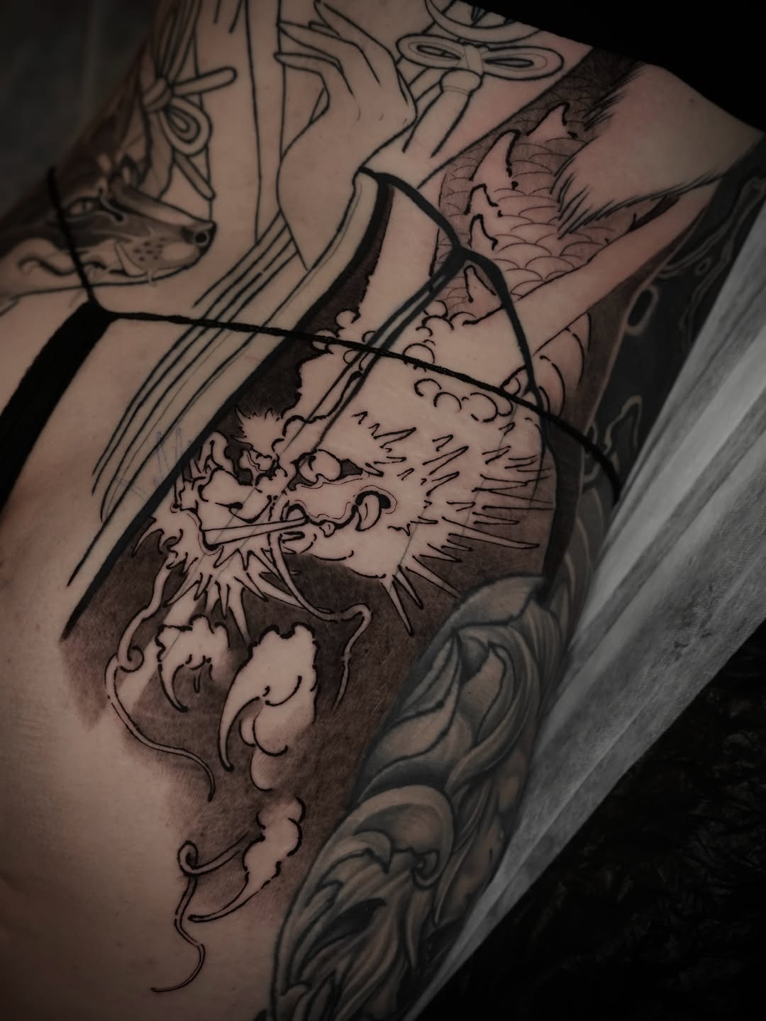 Demonic creature with horns and detailed shading on upper arm, rendered in black and grey with smooth gradient transitions.