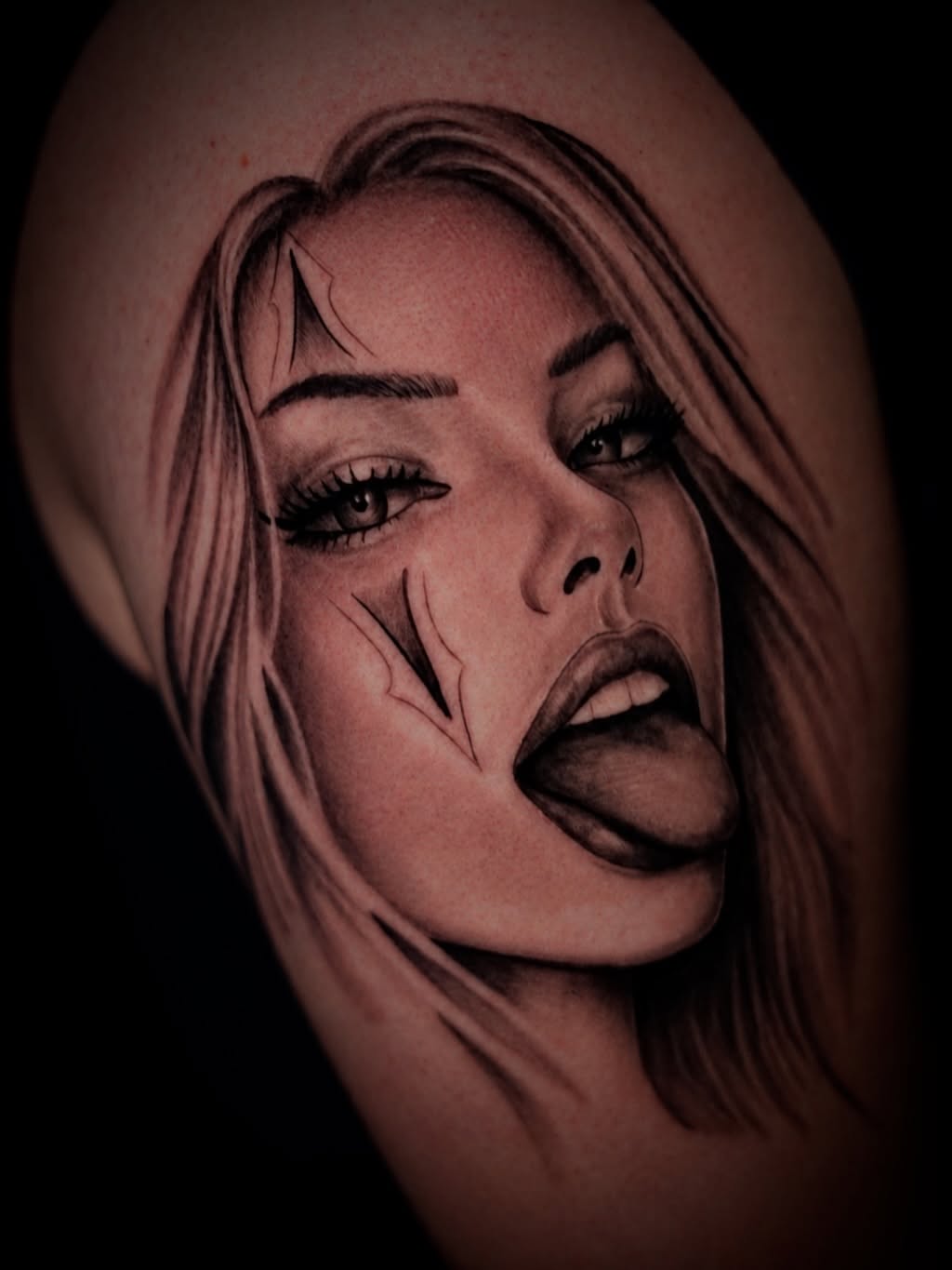Side profile portrait of a woman with long hair and dramatic facial features rendered in black and grey shading on skin.