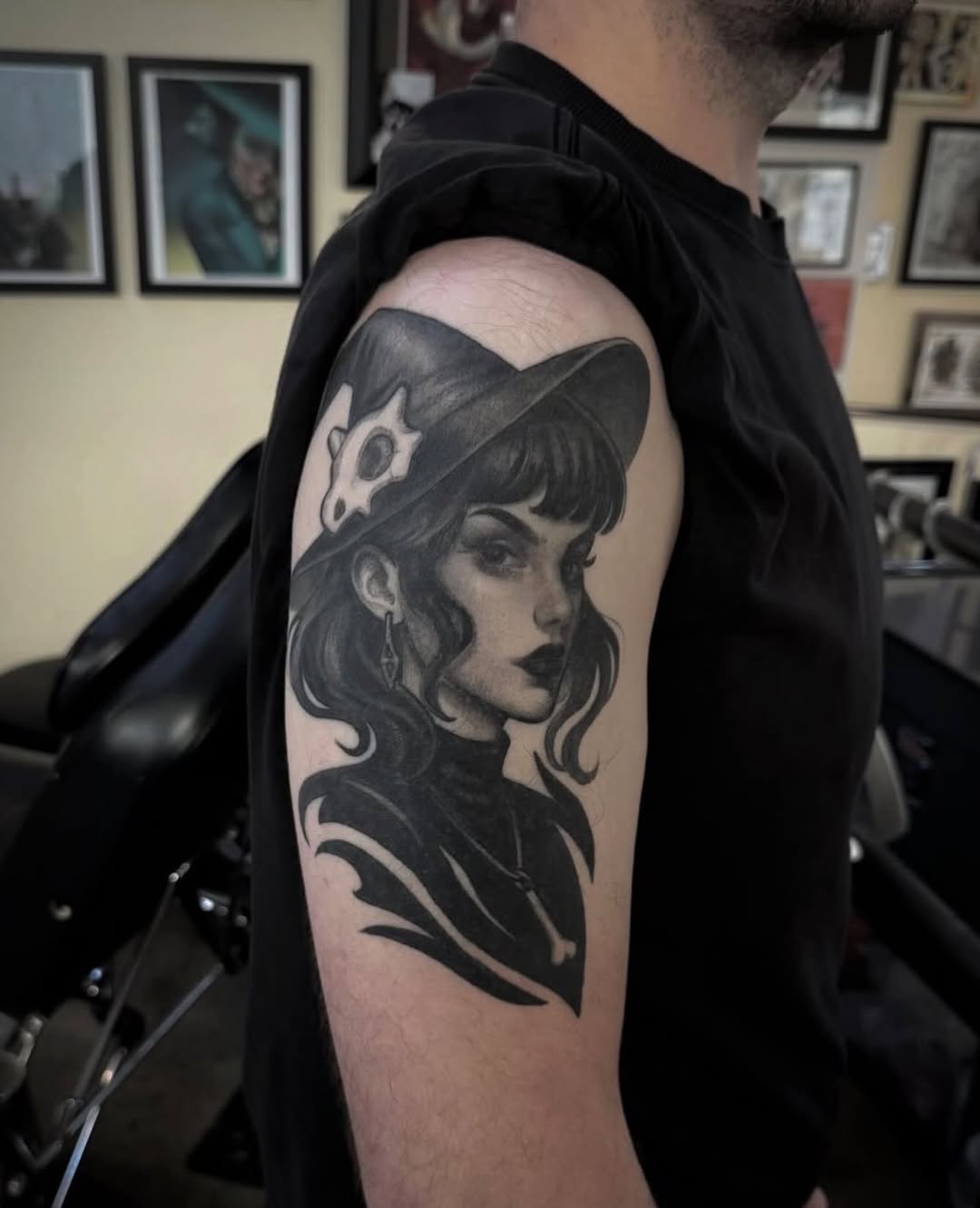 Black and grey portrait tattoo of a woman with wavy hair and decorative headpiece on upper arm, featuring soft shading.