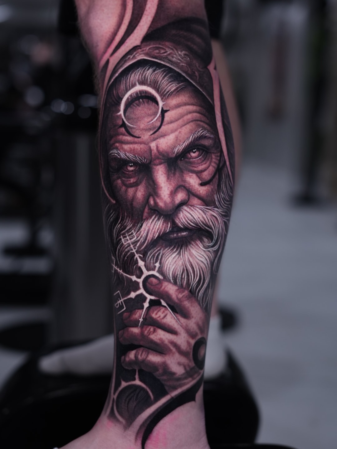 Detailed black and grey portrait of an elderly bearded man with a monocle on the forearm, rendered with smooth shading and realistic features.