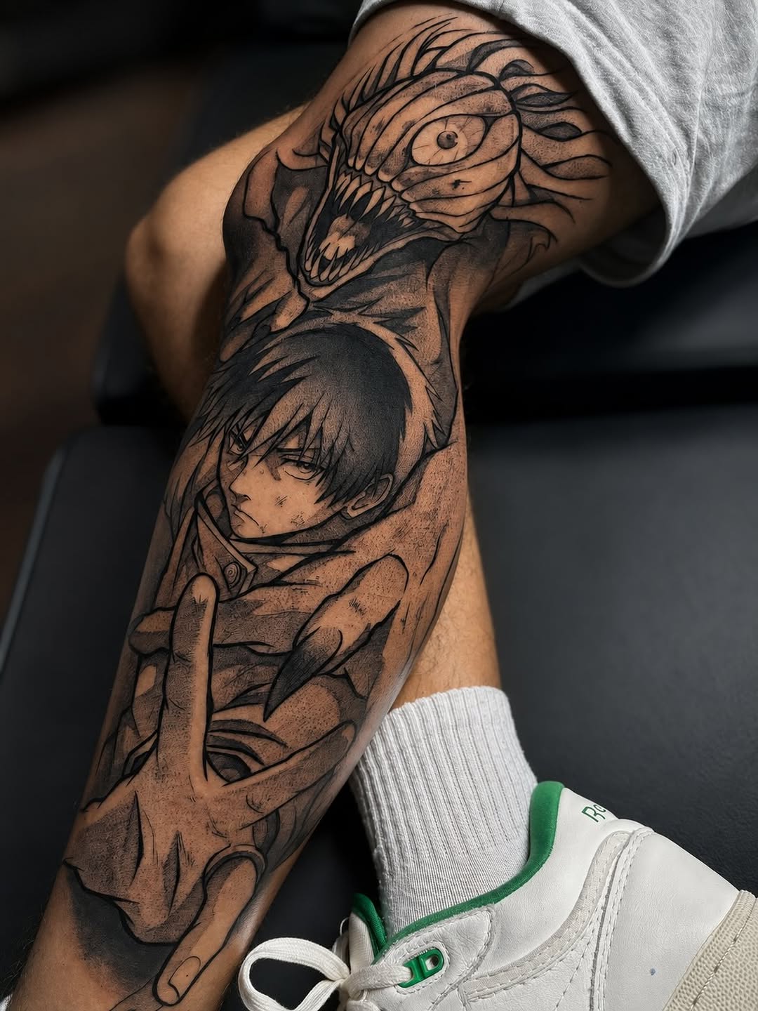 Anime-inspired character portrait and dragon head tattoo on forearm with smooth black and grey shading and detailed line work.