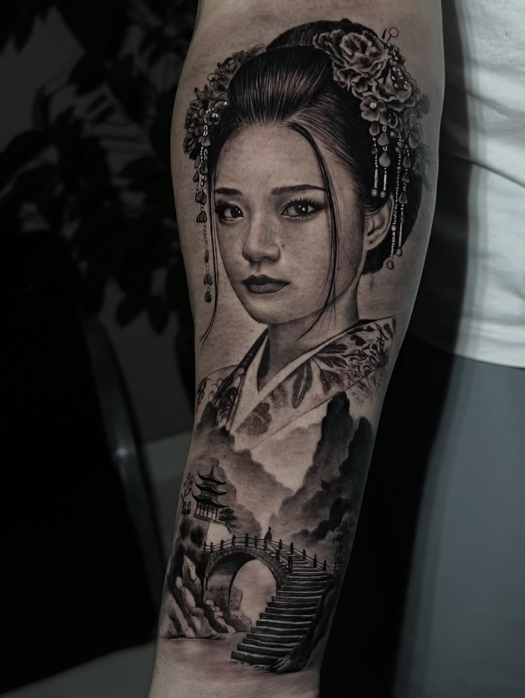 Woman's portrait with traditional Asian headdress and floral ornaments, with pagoda landscape below on leg in black and grey.