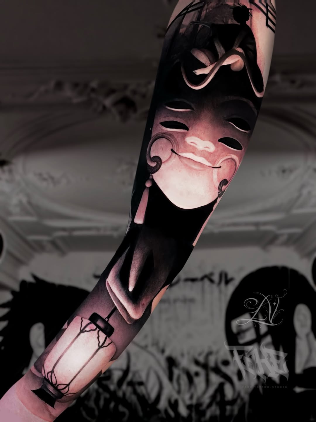Arm tattoo featuring two theatrical masks with ornate details and fine line work in black and grey shading on skin.