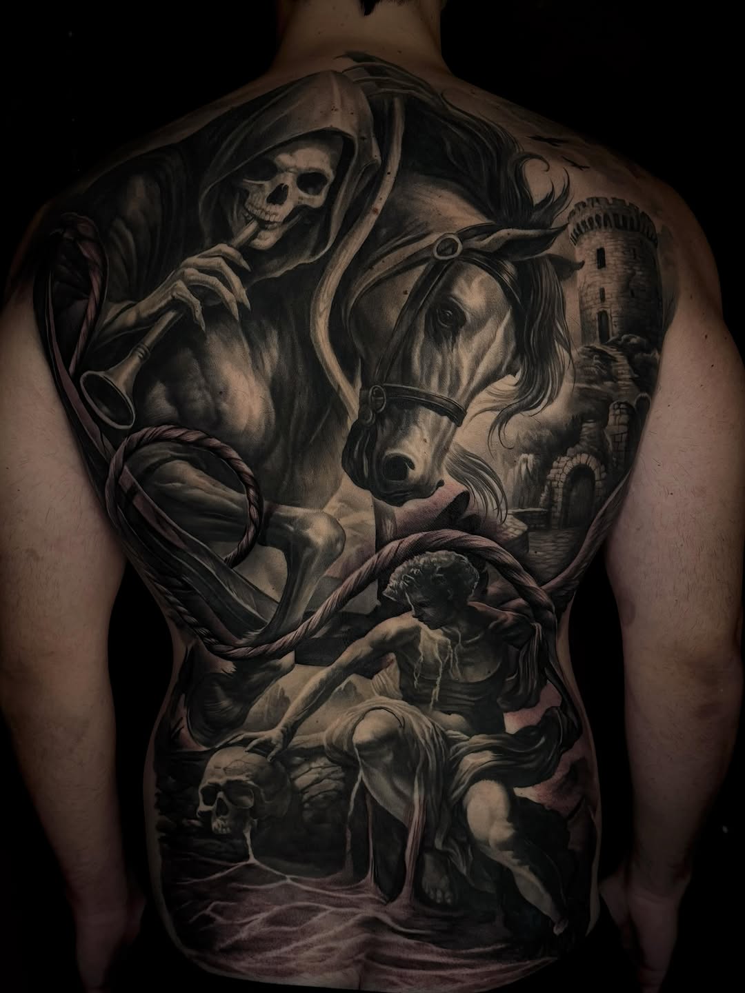 Full back tattoo featuring Grim Reaper, galloping horse, castle tower, cherub statue, and skull in black and grey realism with smooth gradient shading.