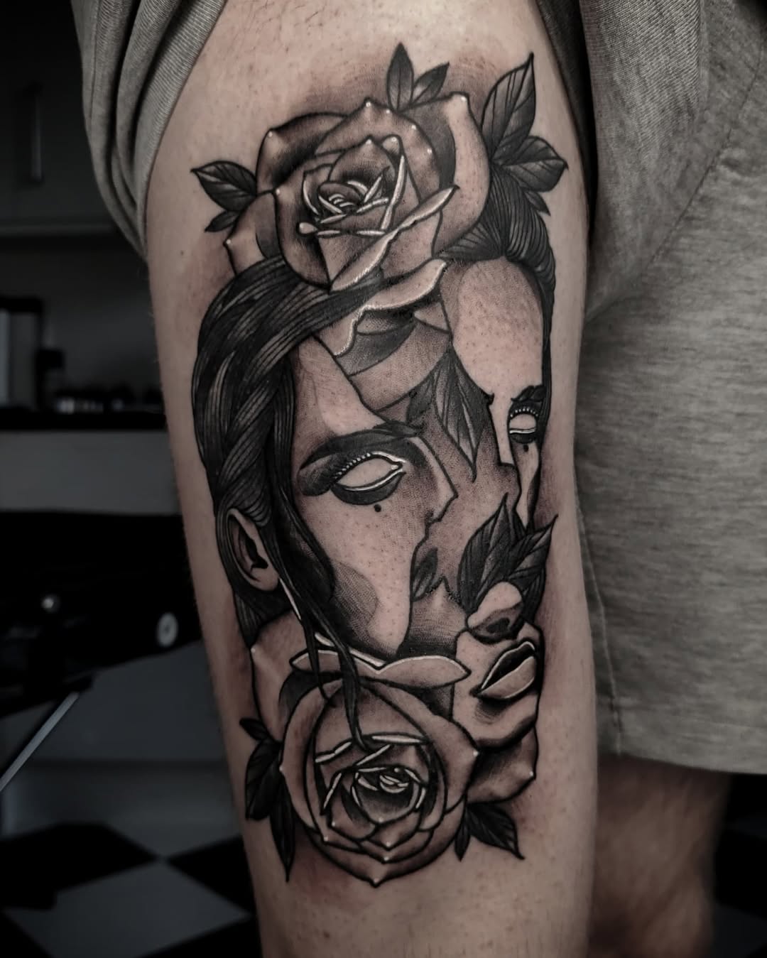 Black and grey portrait tattoo on thigh featuring a woman's face with roses, detailed shading and realistic features.