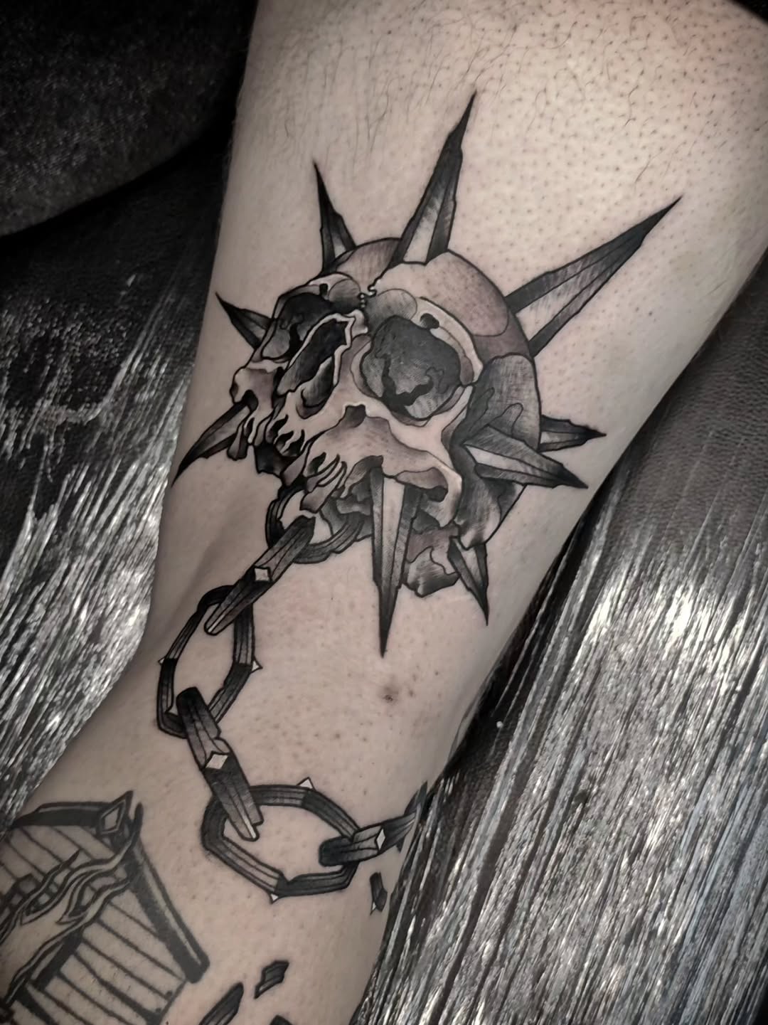 Demonic skull with spikes and horns on forearm, rendered in black and grey with smooth shading and dimensional detail.