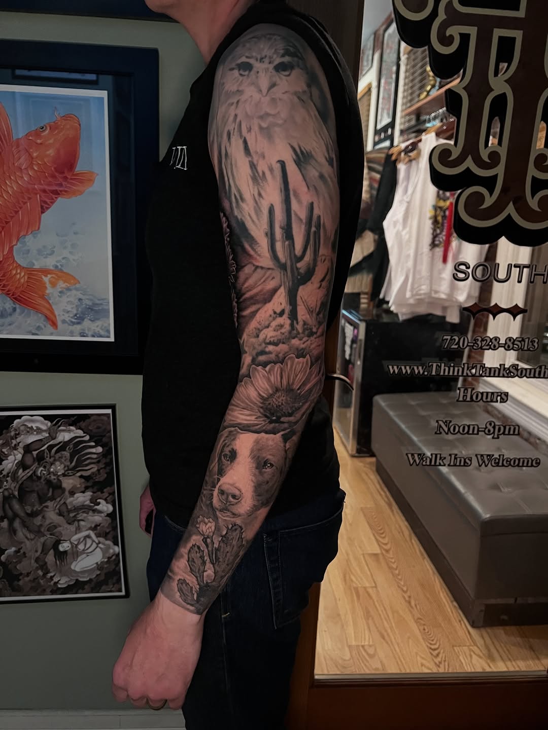 Full black and grey sleeve tattoo featuring an owl, dog portrait, sunflower, and botanical elements on the upper arm.