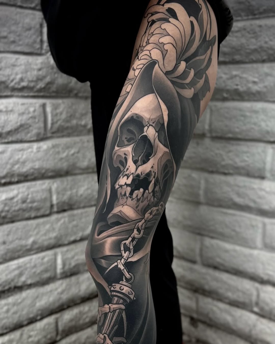 Full leg sleeve tattoo featuring a skull with flowing organic elements and a dagger, executed in black and grey realism with smooth shading.