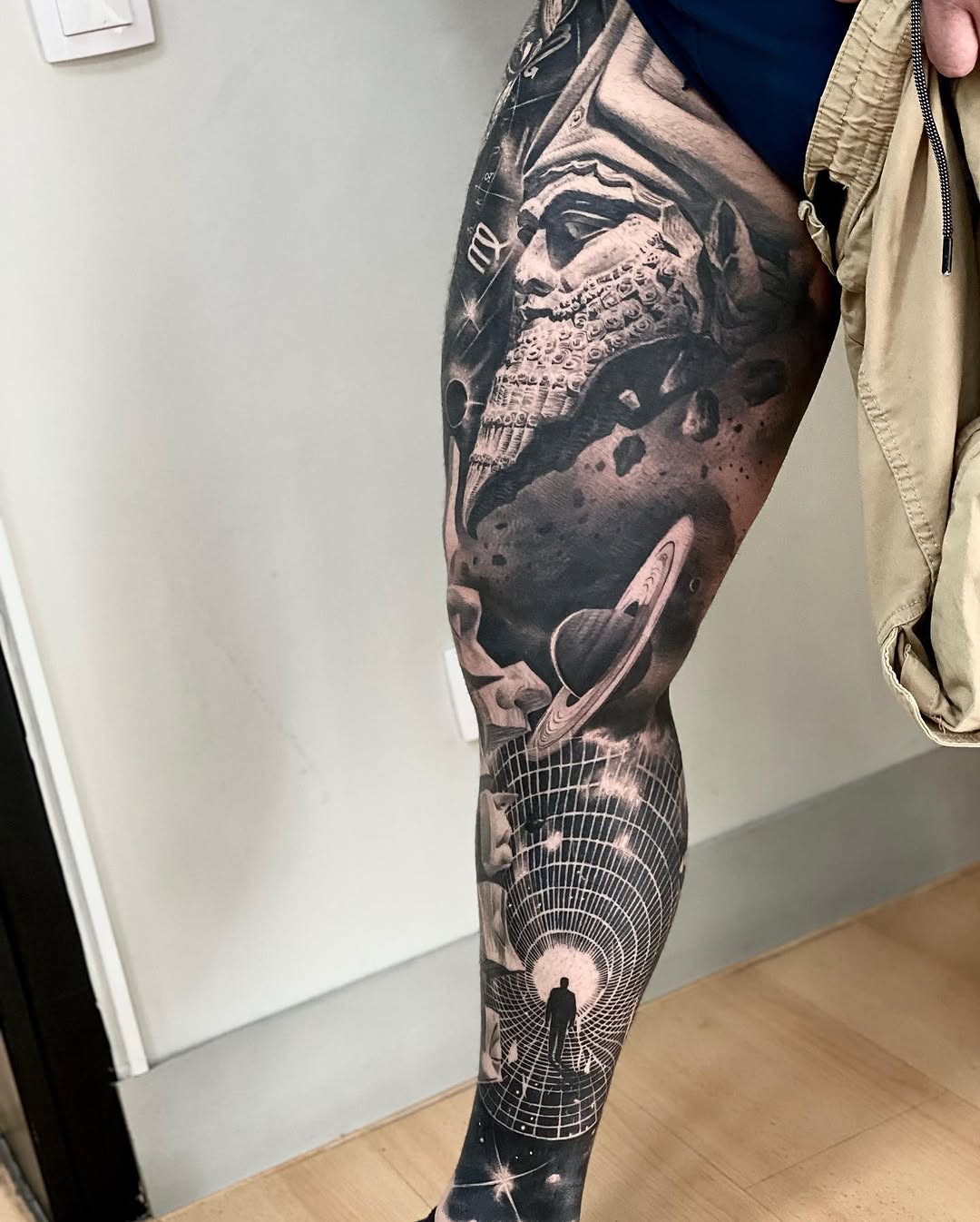 Full leg tattoo sleeve featuring a bearded man's portrait, planets, and a cosmic tunnel with a silhouetted figure, rendered in black and grey.