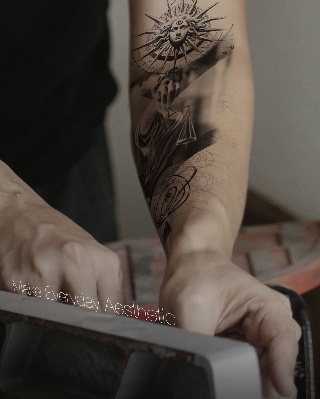 Black and grey tattoo on calf featuring a sun face with radiating spikes above a draped figure with ornamental details below.
