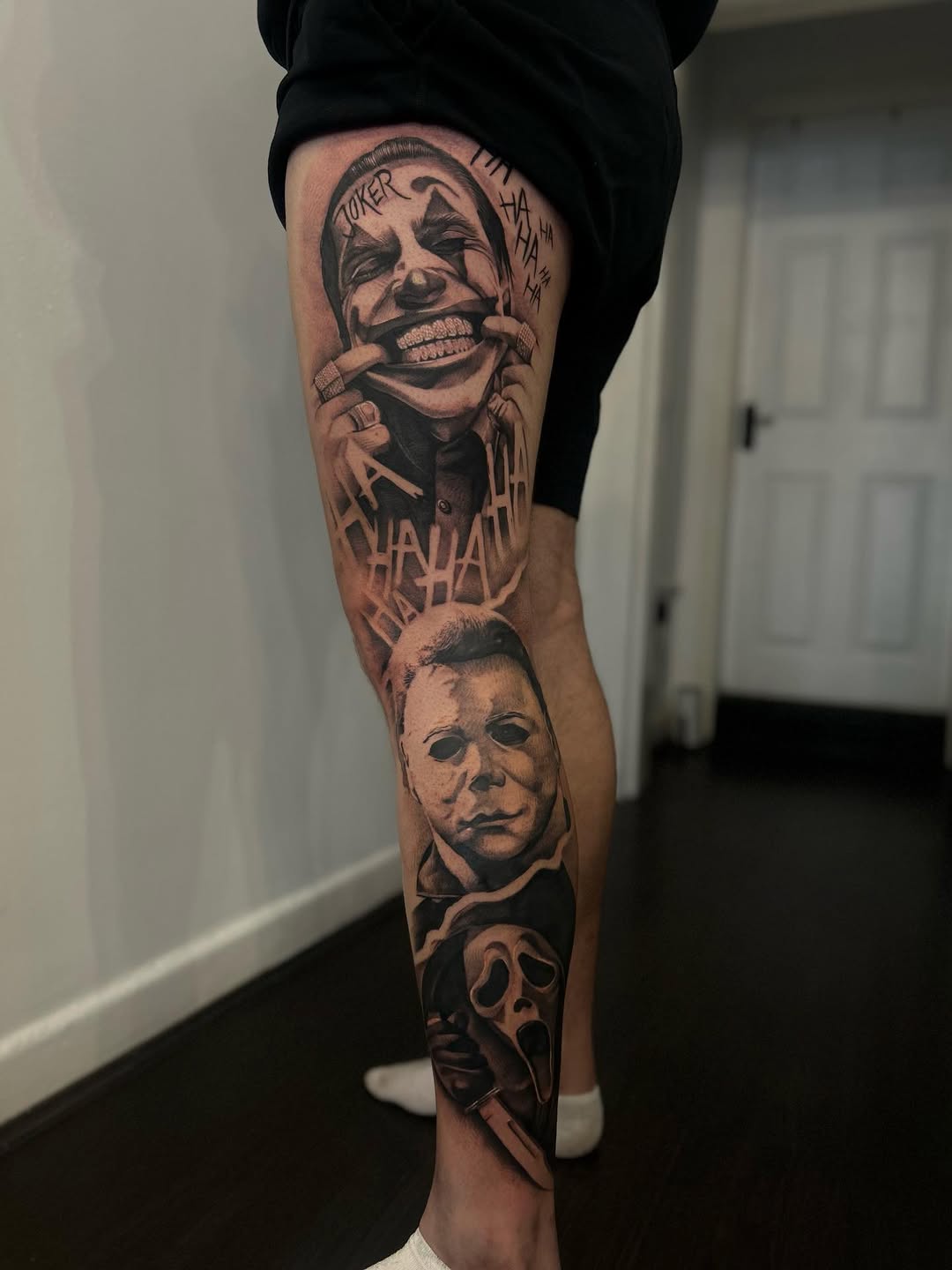 Full leg tattoo sleeve featuring horror movie characters with smooth black and grey shading, including clown and masked figures with text elements.
